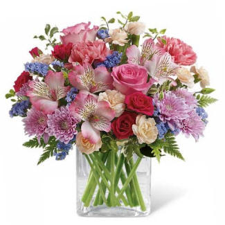pink alstroemeria flowers mixed with mums, roses and other flowers in a clear vase