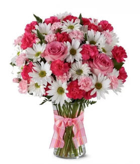 White dasies, red carnations and pink roses in a clear vase with a pink bow