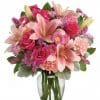 Light pink lilies, roses and carnations in a clear glass vase.