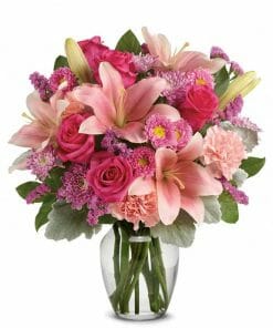 Light pink lilies, roses and carnations in a clear glass vase.