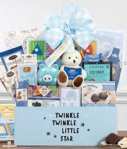 A blue gift box with a white ribbon and a "Sweetest New Baby" tag, filled with an assortment of baby items.