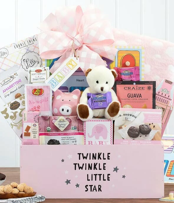 a pink gift box filled with essentials including teddy bears, snacks a piggy bank and more.