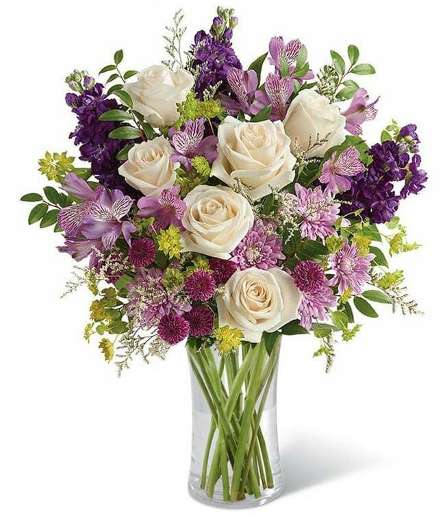Lushful bouquet of purple roses, lavender alstroemeria, purple stock, purple button chrysanthemums, lavender cushion spray chrysanthemums, white limonium, bupleurum, and huckleberry in a cylinder vase - Hand-delivered by a local florist.