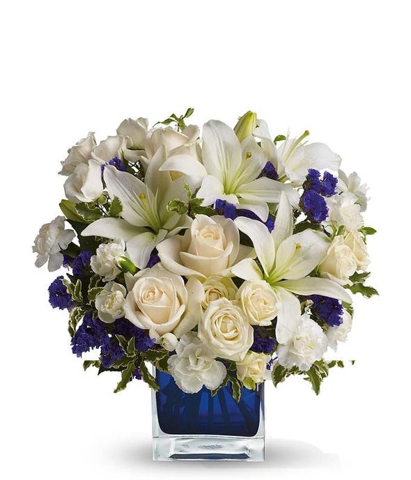 A cubed vase filled with with and blue flowers