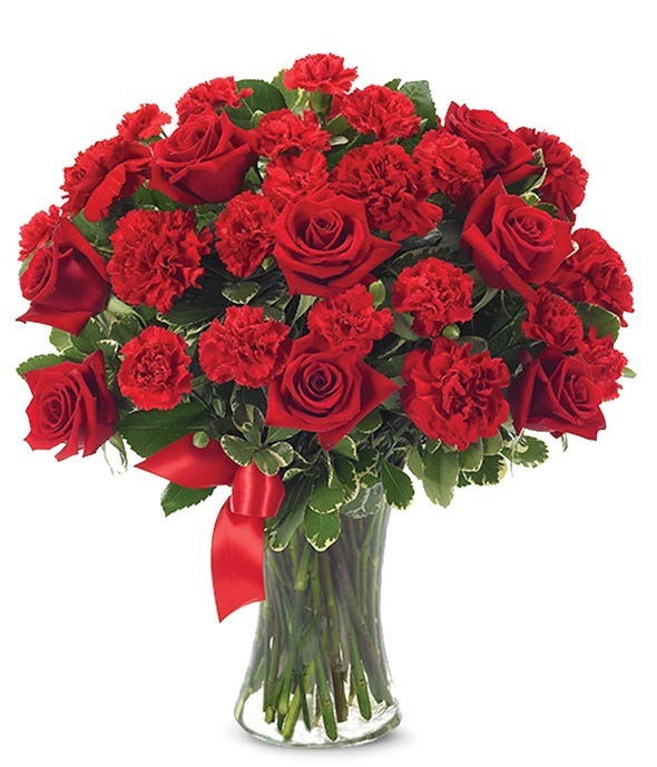 A blend of red roses and red carnations with greenery in a flower bouquet.